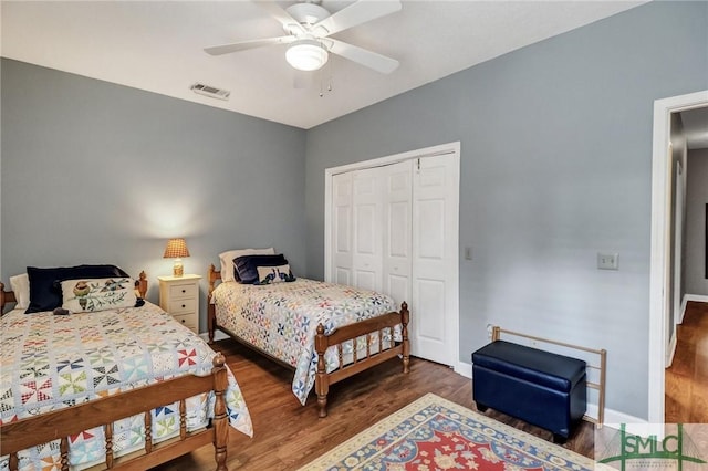 bedroom with baseboards, visible vents, dark wood finished floors, and a closet