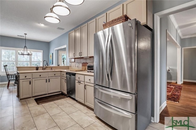 kitchen with stainless steel appliances, a sink, light countertops, tasteful backsplash, and pendant lighting