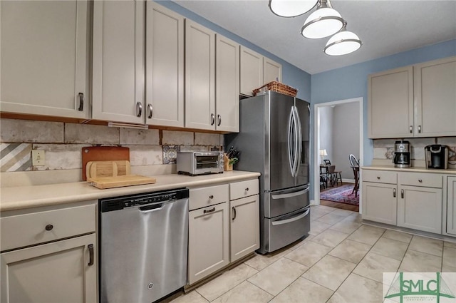 kitchen with light tile patterned floors, a toaster, light countertops, appliances with stainless steel finishes, and backsplash