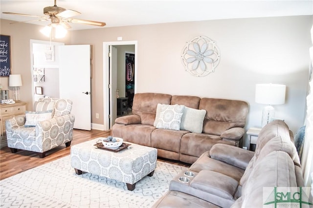 living room with light wood finished floors, a ceiling fan, and baseboards