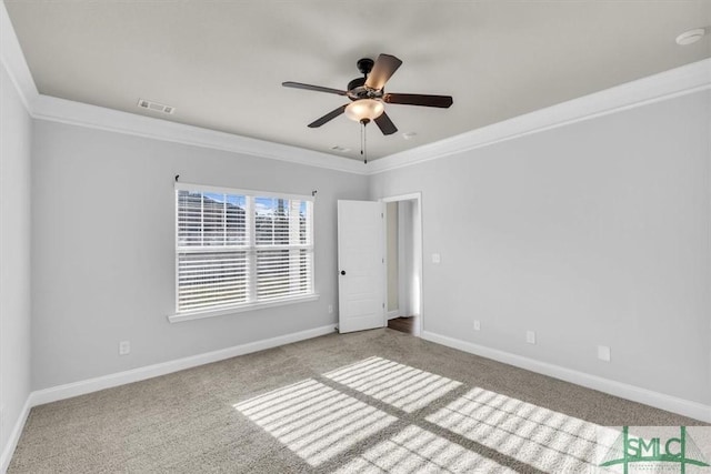 empty room featuring carpet floors, crown molding, visible vents, a ceiling fan, and baseboards