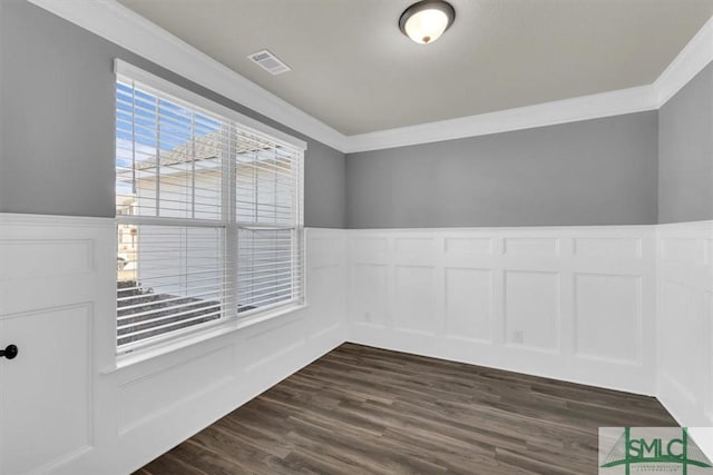 spare room featuring a decorative wall, a wainscoted wall, dark wood-style flooring, visible vents, and crown molding