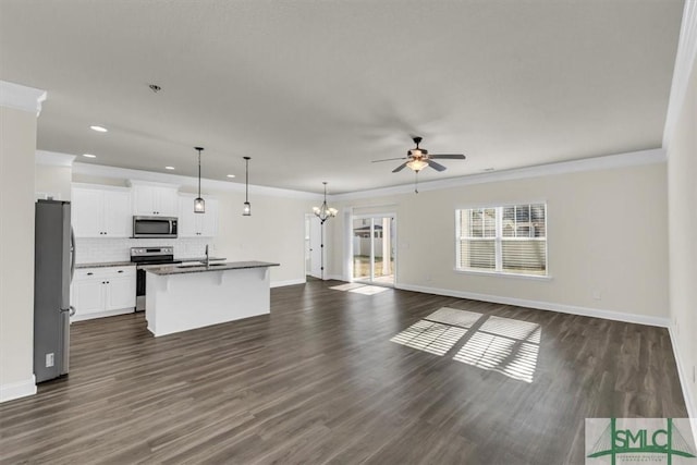 kitchen featuring dark countertops, appliances with stainless steel finishes, open floor plan, a kitchen island with sink, and white cabinets