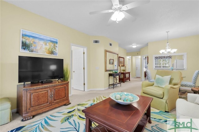 living area with baseboards, ceiling fan with notable chandelier, visible vents, and light colored carpet