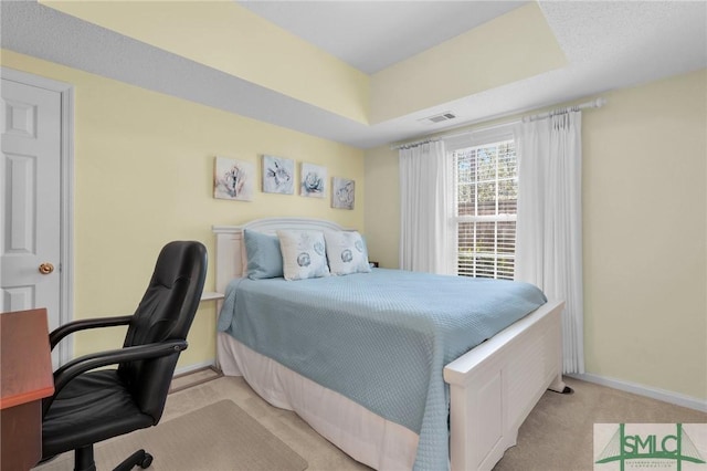 bedroom with light carpet, baseboards, visible vents, and a tray ceiling