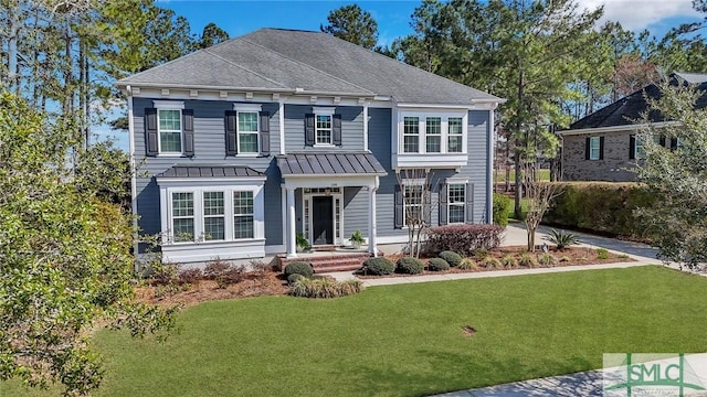 view of front facade with a standing seam roof, roof with shingles, metal roof, and a front lawn