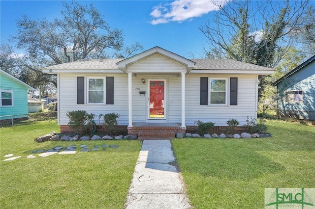 bungalow-style home featuring a front yard, roof with shingles, and fence