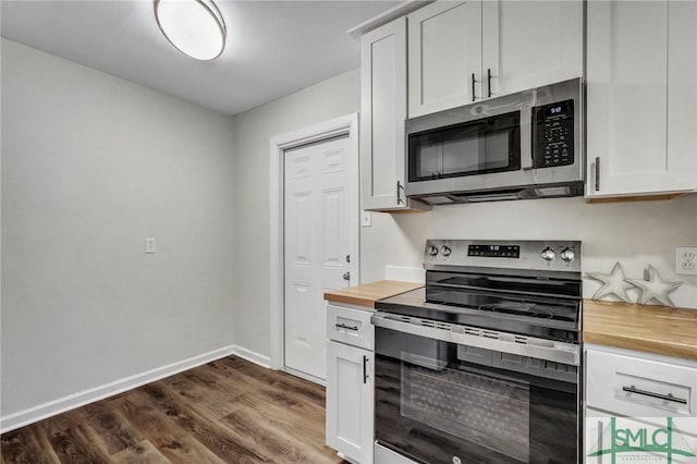kitchen featuring wooden counters, dark wood-style floors, baseboards, appliances with stainless steel finishes, and white cabinetry