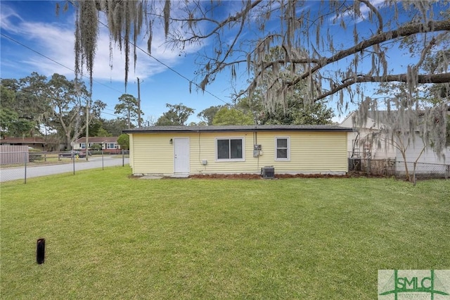 back of property featuring a fenced backyard, a lawn, and central AC