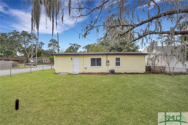 back of property featuring a fenced backyard, a yard, and central AC