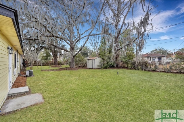 view of yard featuring a storage shed, central AC, an outbuilding, and fence