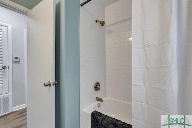 bathroom featuring wood finished floors, visible vents, and shower / bathtub combination with curtain