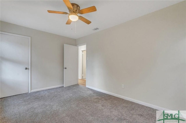 unfurnished bedroom with carpet floors, a ceiling fan, visible vents, and baseboards