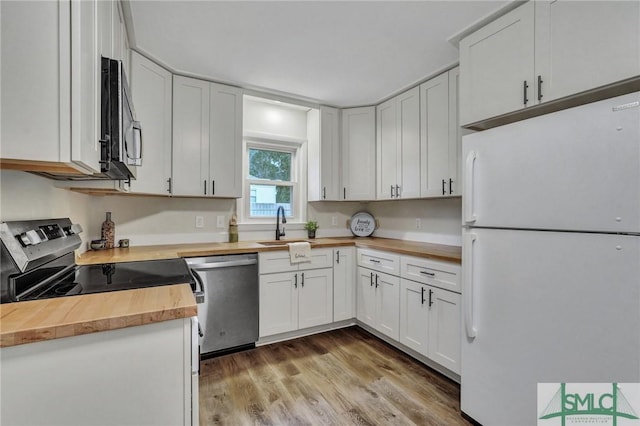 kitchen featuring white cabinets, stainless steel appliances, a sink, light wood-type flooring, and wood counters