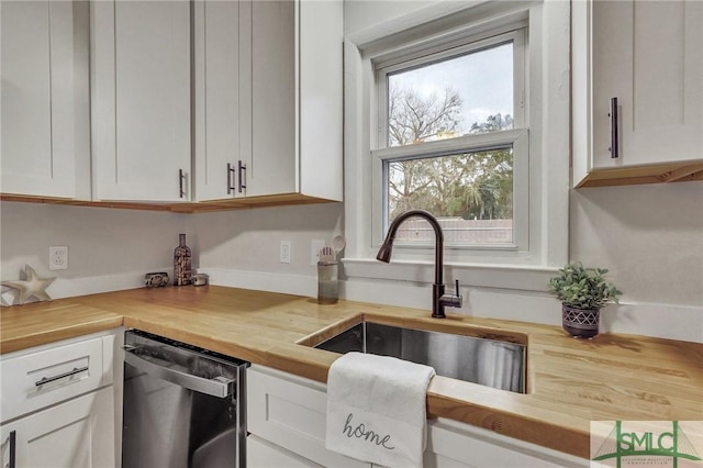 kitchen featuring butcher block counters, white cabinetry, dishwasher, and a sink