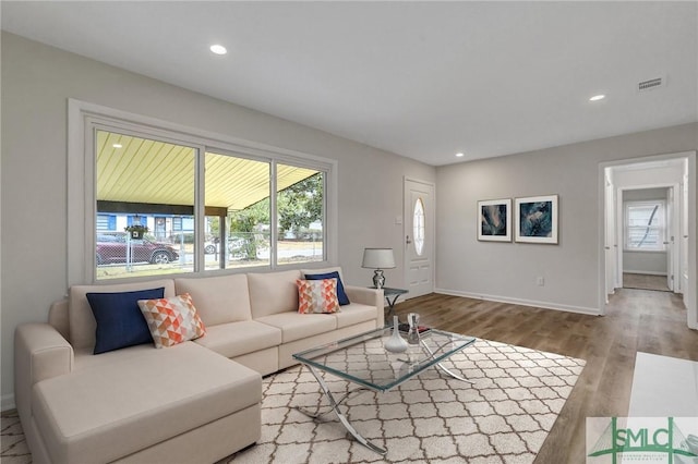 living area with recessed lighting, visible vents, baseboards, and wood finished floors