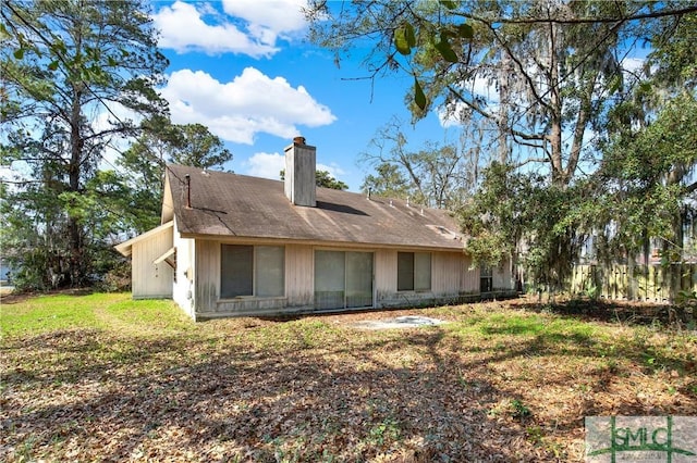 back of property with a chimney and a lawn