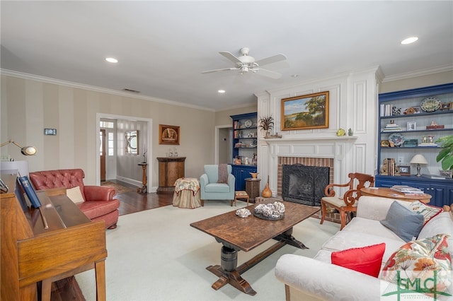 living area with visible vents, light wood-style flooring, ornamental molding, a fireplace, and recessed lighting