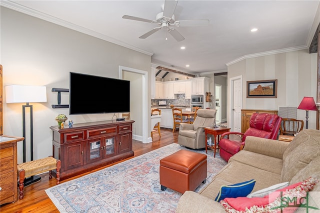 living room with light wood finished floors, baseboards, ceiling fan, crown molding, and recessed lighting