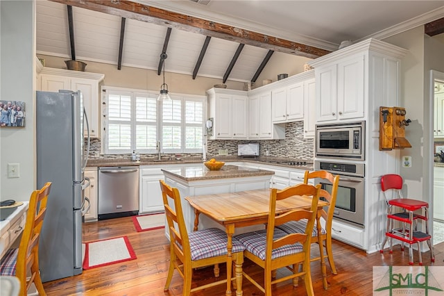 kitchen with vaulted ceiling with beams, a sink, white cabinetry, appliances with stainless steel finishes, and decorative backsplash