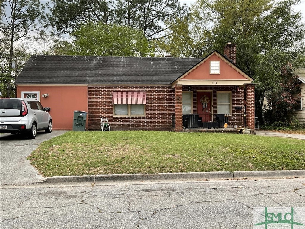 view of front of home featuring brick siding, a chimney, and a front lawn