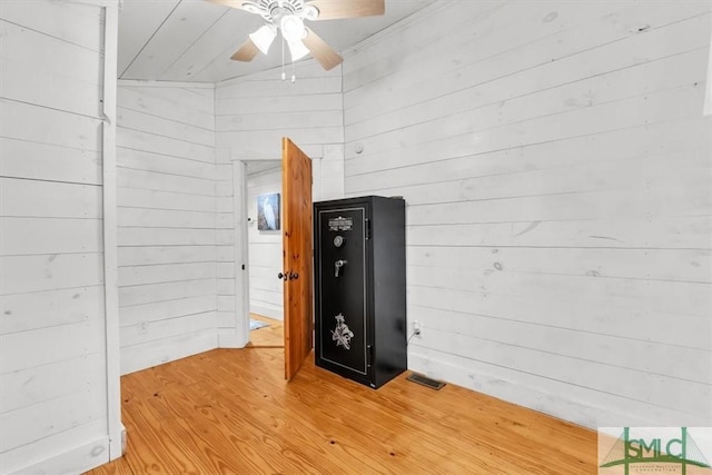 interior space featuring a ceiling fan, wood finished floors, visible vents, and wooden walls