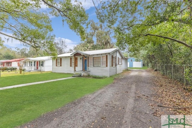 view of front facade with driveway, fence, and a front lawn