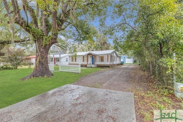 manufactured / mobile home with driveway, fence, and a front yard