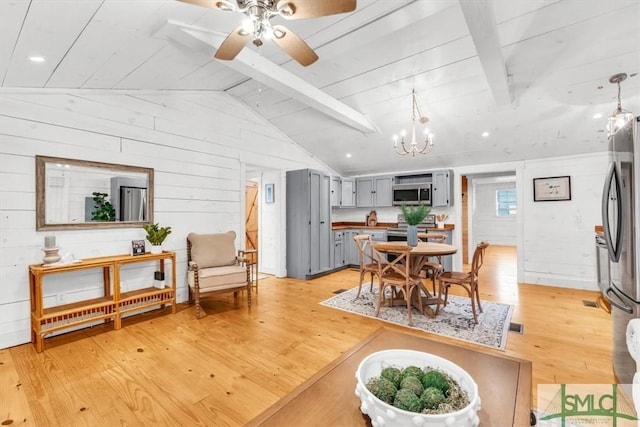 dining room featuring wooden walls, visible vents, vaulted ceiling with beams, light wood-style floors, and ceiling fan with notable chandelier