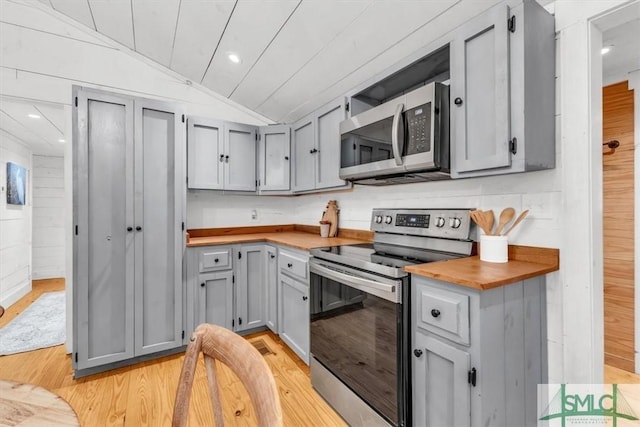 kitchen featuring light wood-style flooring, vaulted ceiling, stainless steel appliances, and gray cabinetry