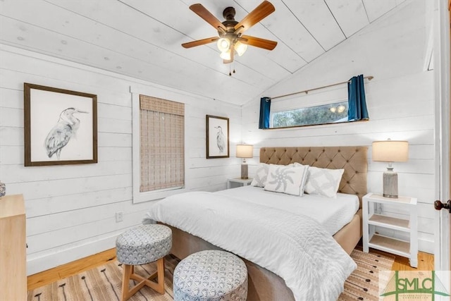 bedroom with lofted ceiling, ceiling fan, wooden walls, wood ceiling, and light wood-type flooring