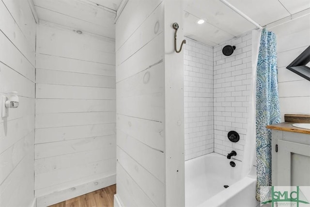 full bath with shower / tub combo, wood walls, wood finished floors, and vanity