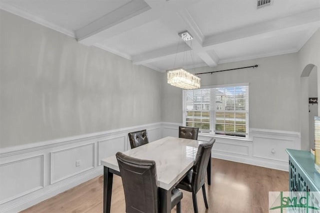 dining area with arched walkways, visible vents, beam ceiling, and light wood-style floors