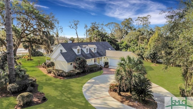 view of front of property with a garage, driveway, a chimney, and a front lawn