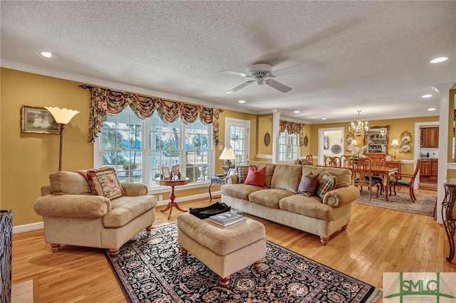 living room with light wood-type flooring, decorative columns, baseboards, and a textured ceiling