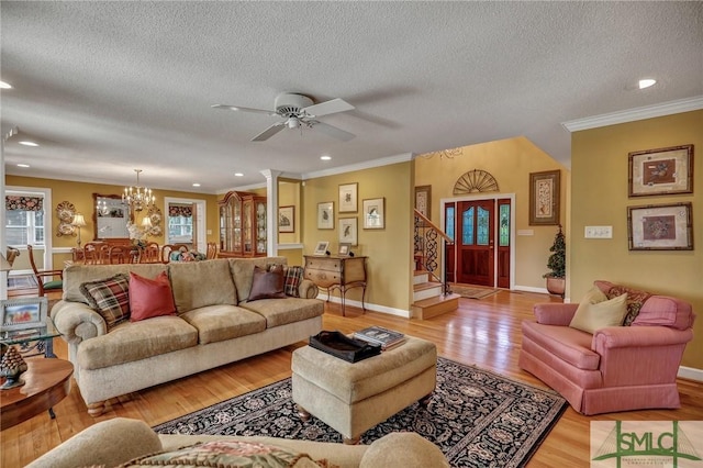 living room featuring a wealth of natural light, light wood-style flooring, stairs, and crown molding