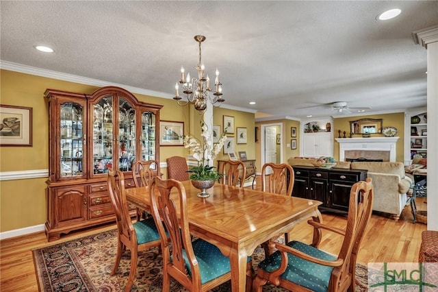 dining space with ornamental molding, a fireplace, and light wood-style flooring