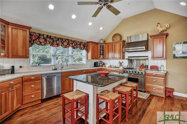 kitchen with wall chimney exhaust hood, a kitchen bar, glass insert cabinets, and stainless steel appliances