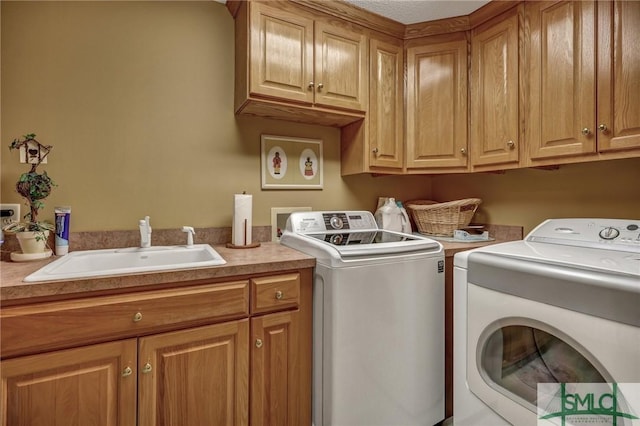 washroom with cabinet space, a sink, and washing machine and clothes dryer