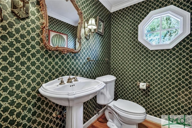 half bath featuring ornamental molding, wood finished floors, toilet, and wallpapered walls