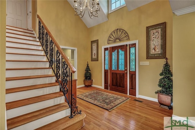 foyer featuring baseboards, wood finished floors, visible vents, and an inviting chandelier