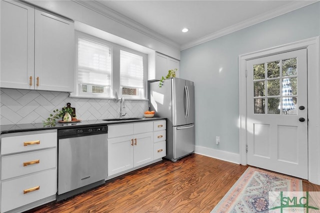 kitchen featuring appliances with stainless steel finishes, dark countertops, a sink, and white cabinets