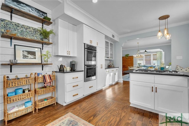 kitchen with white cabinets, dark countertops, appliances with stainless steel finishes, glass insert cabinets, and pendant lighting