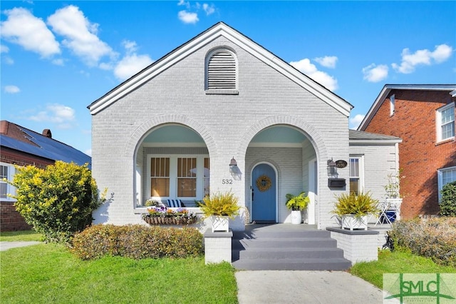 view of front facade with covered porch, brick siding, and a front lawn