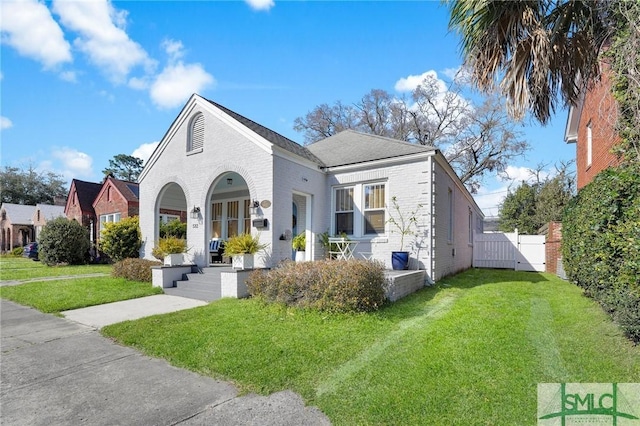 view of front of house featuring fence, a front lawn, a porch, and brick siding