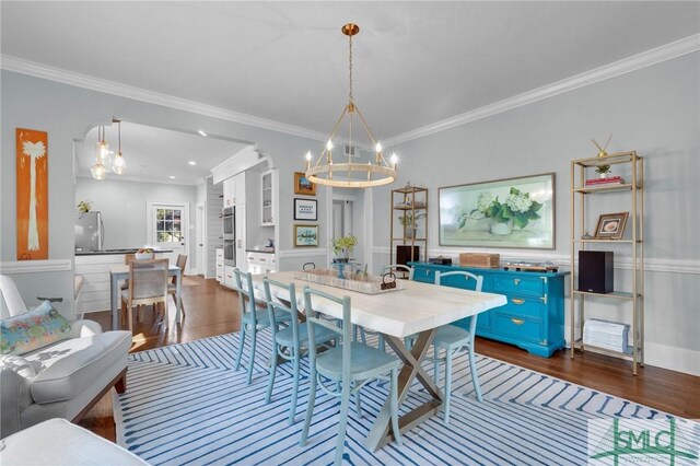 dining area featuring crown molding, dark wood finished floors, and an inviting chandelier