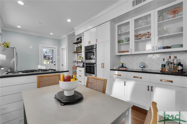 kitchen with visible vents, white cabinets, appliances with stainless steel finishes, glass insert cabinets, and backsplash