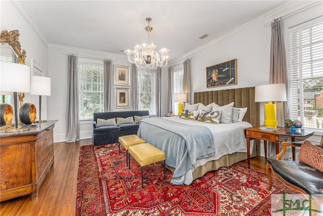 bedroom with a chandelier, wood finished floors, visible vents, and crown molding