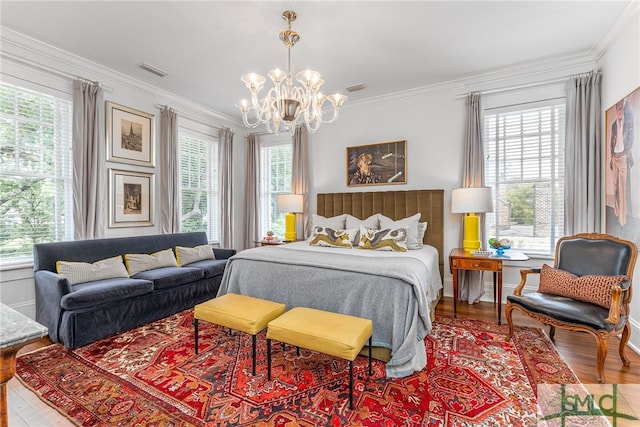 bedroom featuring ornamental molding, multiple windows, wood finished floors, and an inviting chandelier