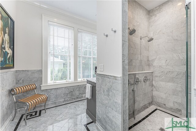 bathroom featuring marble finish floor, tiled shower, wainscoting, and tile walls